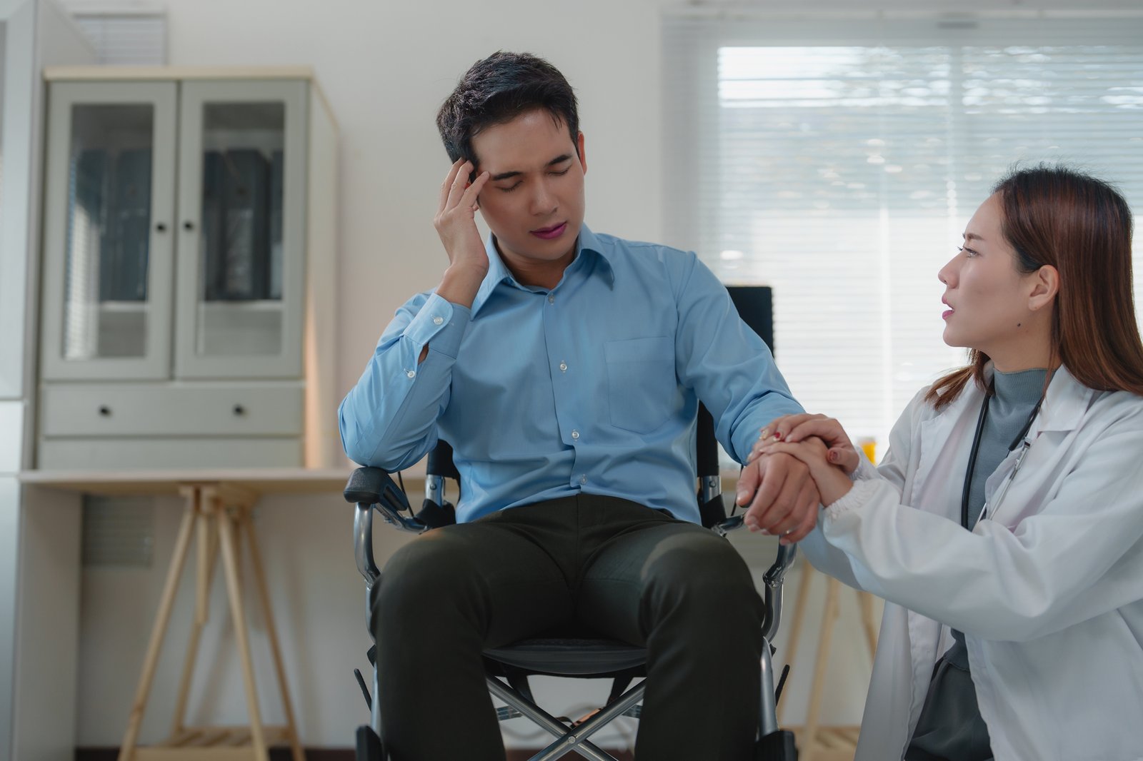 Doctor comforting a suffering patient in wheelchair at hospital